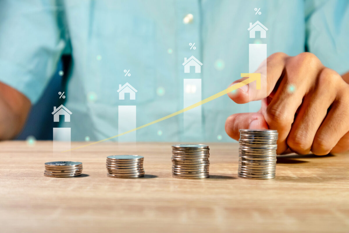 Man with coins on the table. House price rising up or real estate property growth concept.